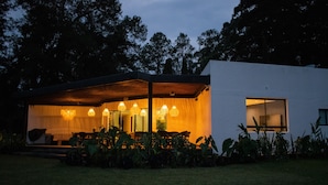 A modern house with a covered patio, large windows, and a well-maintained lawn. - Monarch Campestre (El Carmen de Viboral)