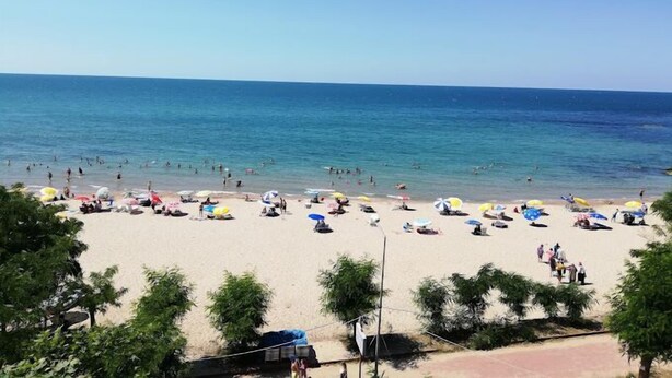 Una playa con gente y sombrillas.