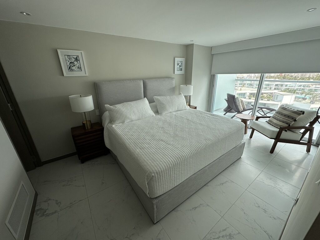 Une chambre d’hôtel moderne dotée d’un grand lit, d’une chaise, d’un bureau et d’un balcon avec vue.