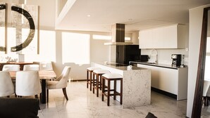 Una cocina moderna con una isla central, taburetes de bar y un comedor con mesa y sillas.