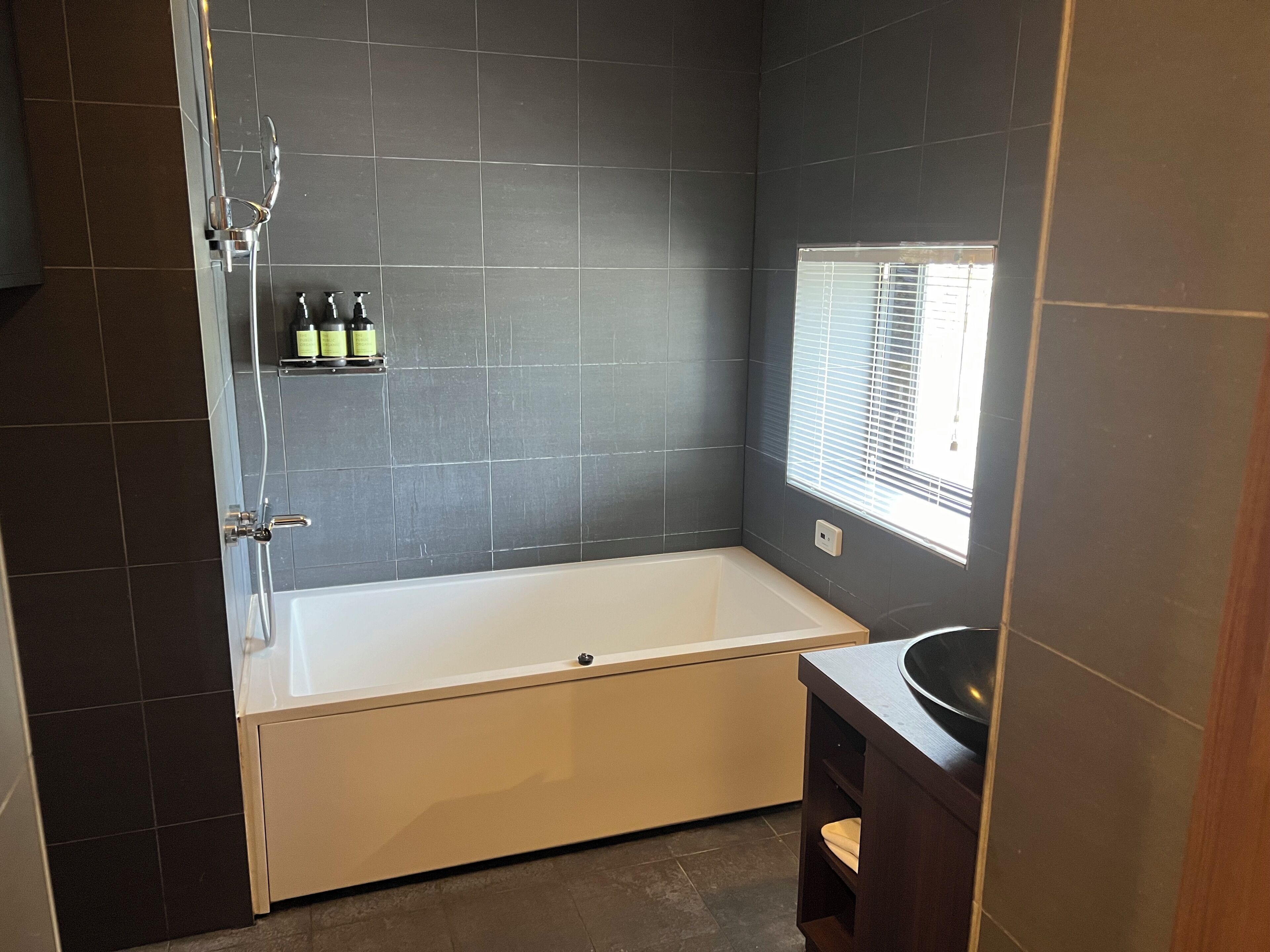 A modern bathroom with a bathtub, a shower, and a window.