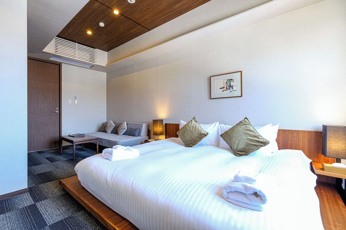 A hotel room with a large bed, bedside tables, a desk, and a chair.