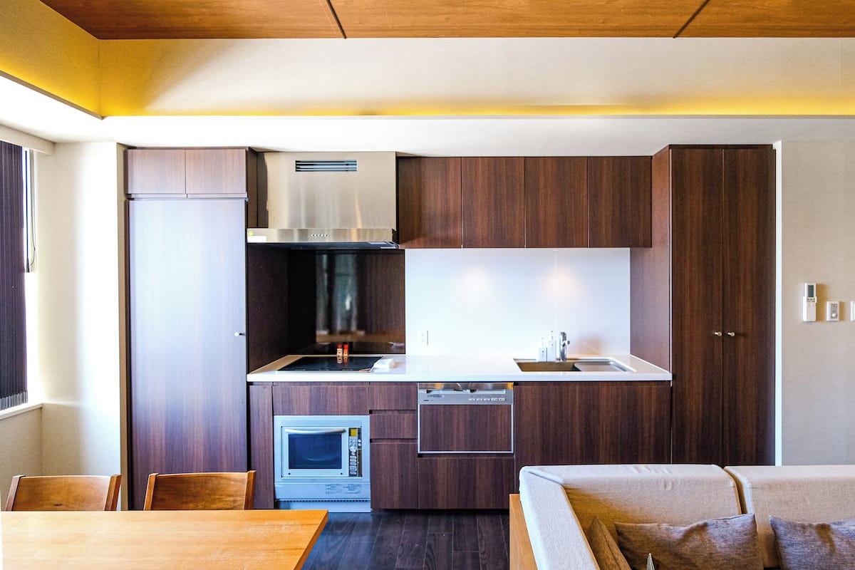 A compact kitchen with a microwave, stove, and sink. There is a dining area with a table and chairs.