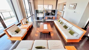 Ein modernes Wohnzimmer mit einer Sofagarnitur, einem Couchtisch und einem Fernseher.