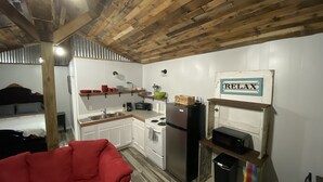 A compact kitchen with white cabinets, a red couch, and a 'RELAX' sign on the wall. - James' Cabin (Gilbert)