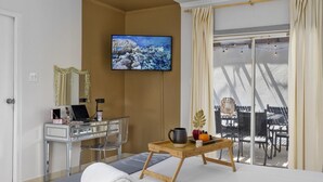 Ein Hotelzimmer mit einem Bett, einem Schreibtisch mit Computer, einem Fernseher und einem Balkon mit Gartenmöbeln.