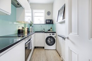 A compact kitchen with a washing machine, a microwave, and a window. - NEW! 2Bed/3Beds/1Bath/Cov Gd Piazza/1 min subway (Greater London)