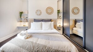 Una camera d'hotel moderna con un letto grande, un comodino con una lampada e specchi decorativi a parete.