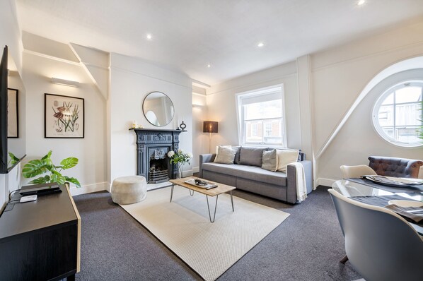 A modern living room with a fireplace, sofa, and dining area. - NEW! 2Bed/3Beds/1Bath/Cov Gd Piazza/1 min subway (Greater London)