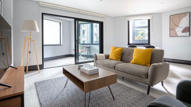 A modern living room with a sofa, coffee table, and floor lamp. - Exceptional Aldgate/Whitechapel 2BR w/ Garden, nr Station, by Blueground (London)