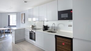 A modern kitchen with white cabinets, a Bosch microwave, a sink, and a dishwasher. - Exceptional Aldgate/Whitechapel 2BR w/ Garden, nr Station, by Blueground (London)
