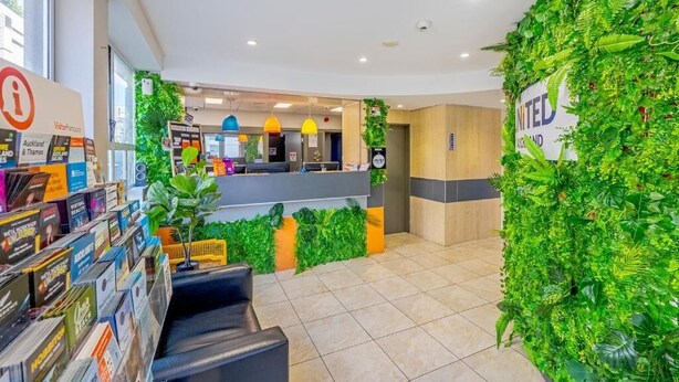 A reception area with a green wall, a counter, and a magazine rack. - United Auckland (Auckland)