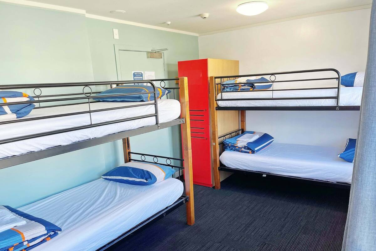 A bunk bed room with a red wardrobe, a door, and a light switch.