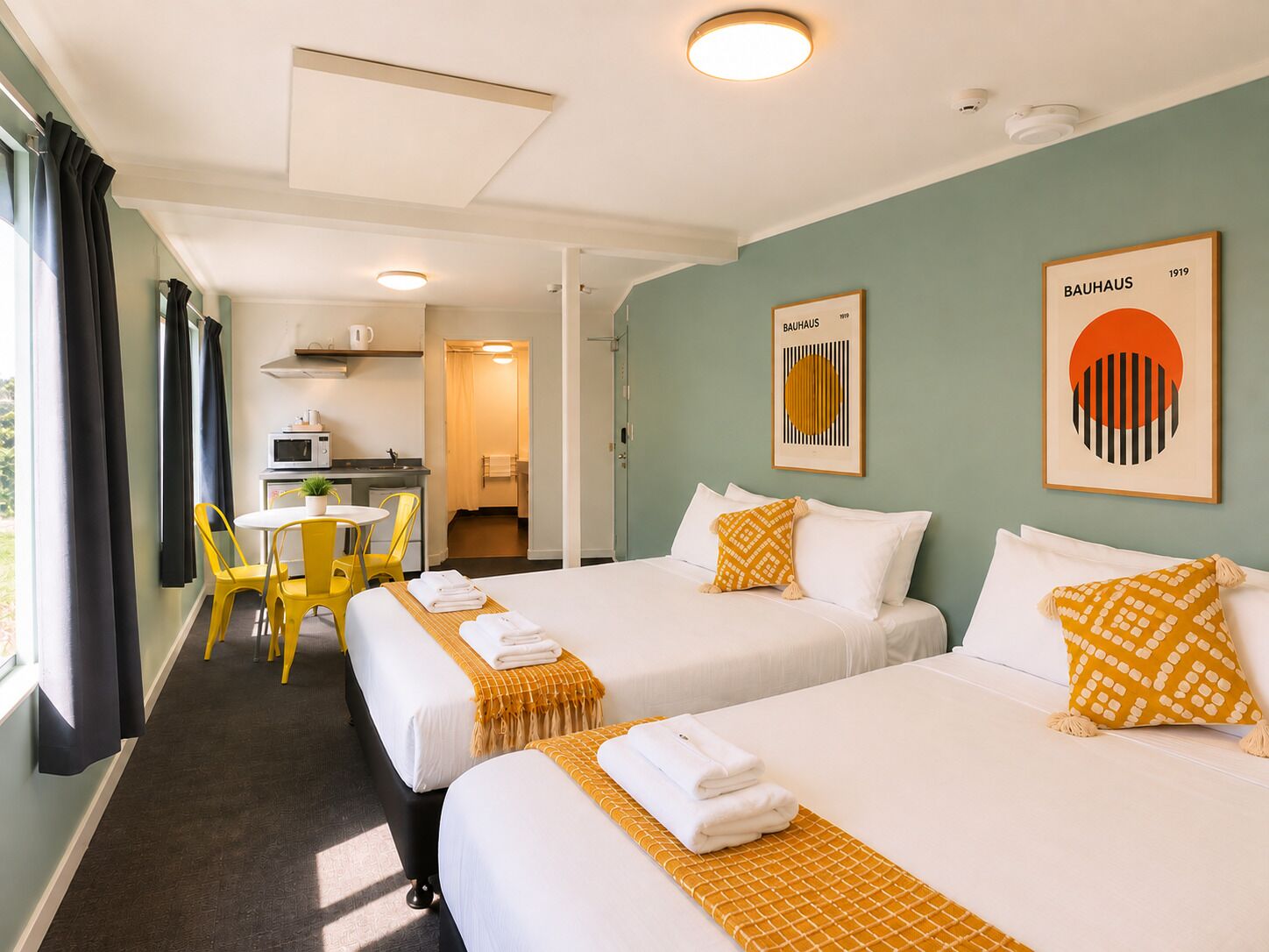 Una habitación de hotel con dos camas, una zona de comedor y una kitchenette.