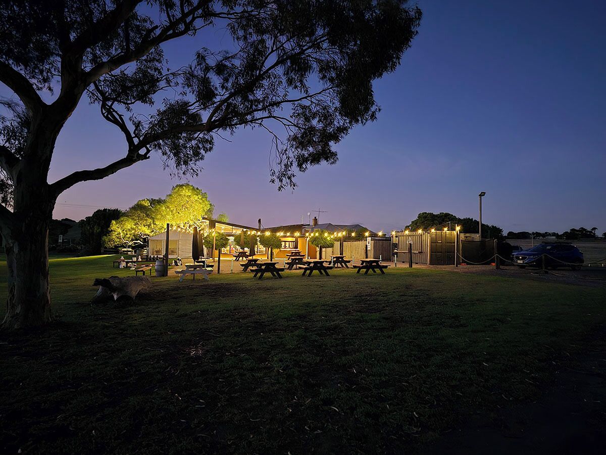 A park with picnic tables and a building with lights.