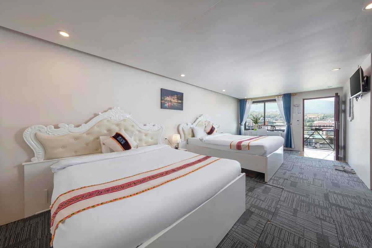 A hotel room with two beds, a large window, and a city view.
