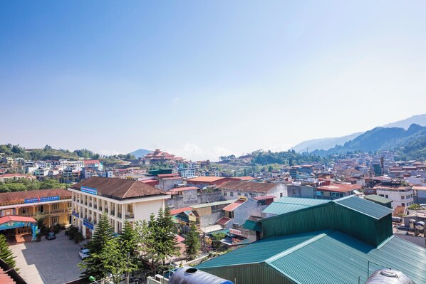 Un pueblo con una mezcla de edificios modernos y tradicionales, cielo despejado y montañas al fondo.