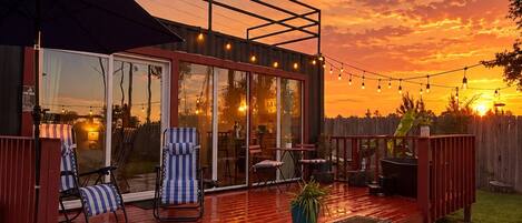 Un patio trasero con jacuzzi, terraza y zona de estar al aire libre.