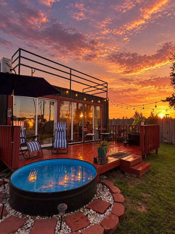 A backyard with a hot tub, deck, and outdoor seating area.