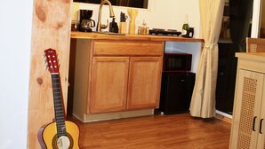 Et køkken med træskabe, en guitar og et skilt med teksten "LA COCINA".
