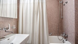 Un baño con ducha, lavamanos y espejo.