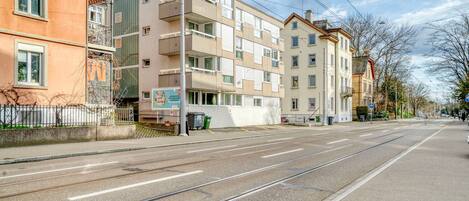 A street with tram tracks, buildings, and a clear sky.