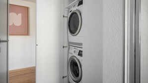 A laundry room with two front-loading washing machines, a wooden floor, and a framed artwork on the wall.