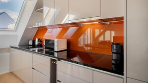 A modern kitchen with a glass countertop, white cabinets, and a view of the outside through a skylight.