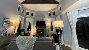 Una sala de estar con chimenea, sofá, televisor y lámpara.