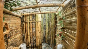 A bamboo-walled bathroom with a stone floor, a toilet, and a basin. - Magic View Prado (Prado)
