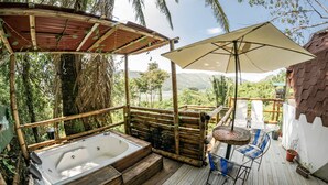 A wooden deck with a hot tub, a table with chairs, and a large umbrella. - Magic View Prado (Prado)