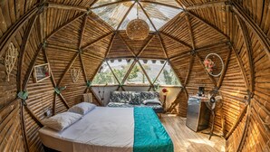 A circular, wooden interior with a bed, a small table, and a fan. - Magic View Prado (Prado)
