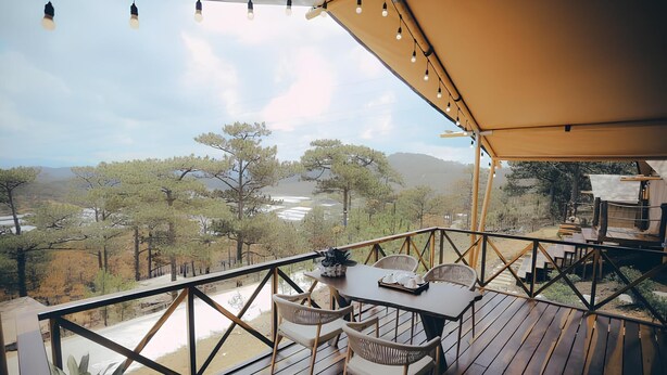 Terraza de madera con mobiliario exterior, con vistas a un paisaje pintoresco con árboles y una masa de agua.