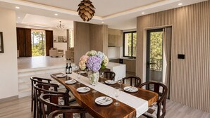 Un comedor con una larga mesa de madera, sillas y un jarrón de flores.