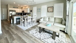 A modern kitchen with white cabinets, a dining area with a white table and chairs, a beige sofa, and a ceiling fan. - Sea View Home 6 bed 3bedroom-garage near boardwalk (Myrtle Beach)