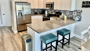 A kitchen with white cabinets, a granite countertop, and a stainless steel refrigerator. - Sea View Home 6 bed 3bedroom-garage near boardwalk (Myrtle Beach)