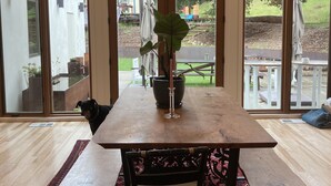 Een eethoek met een houten tafel, twee stoelen, een potplant en een kaars.