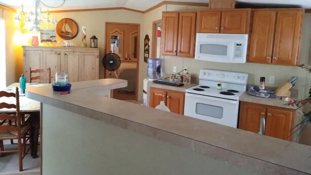 A kitchen with wooden cabinets, a microwave, a stove, and a water dispenser. - Only10 minute walk to the Inland side of Sound, 3 mile  Emerald Isle Beach,Pets (Cape Carteret)