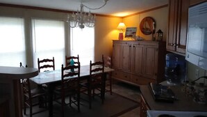 A kitchen with wooden cabinets, a dining table with chairs, a chandelier, and a water dispenser. - Only10 minute walk to the Inland side of Sound, 3 mile  Emerald Isle Beach,Pets (Cape Carteret)