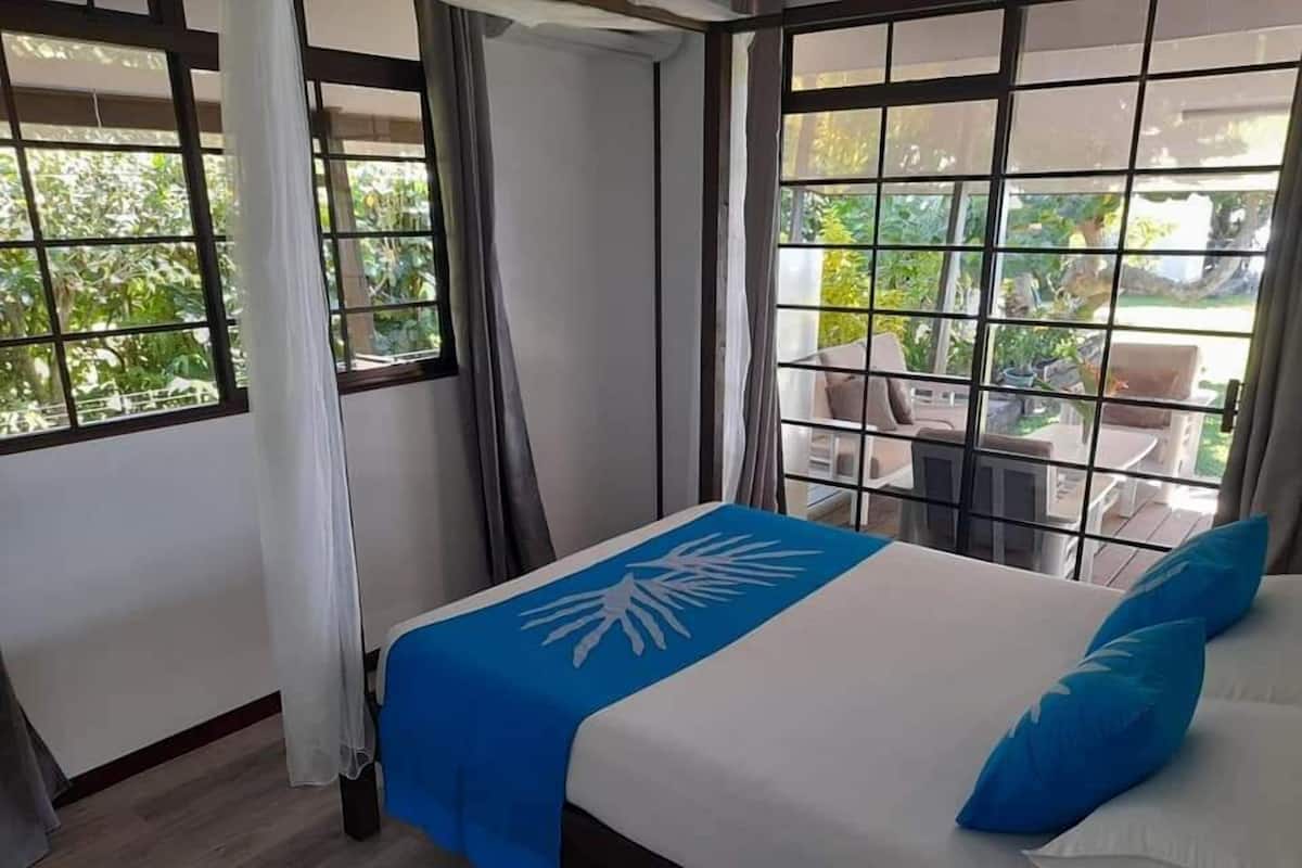 A bedroom with a bed, curtains, and a view of the outdoors.