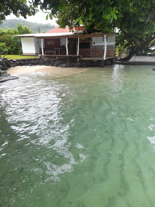 Una casa con tetto rosso e parete in pietra, parzialmente sommersa in acqua cristallina.