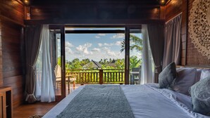 A bedroom with a large bed, wooden walls, and a view of a tropical landscape through a sliding door. - D&B Mandala Villas (Ubud)