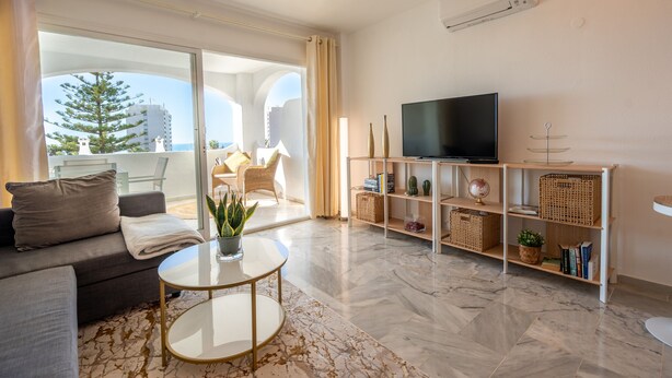 A modern living room with a sofa, coffee table, and TV stand. - Apartment Sleeps 4 with Sea Views (Benalmadena)
