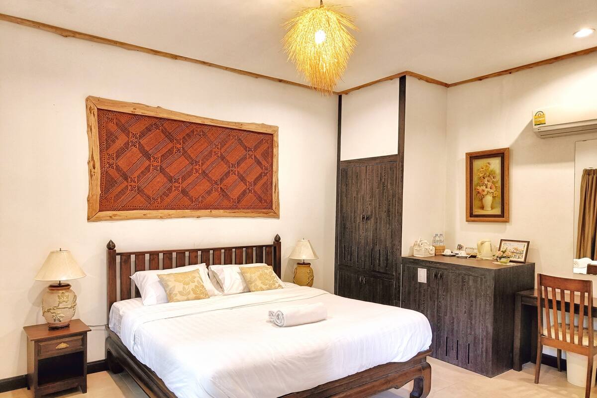 A bedroom with a wooden bed, two bedside tables, a desk, and a chair.