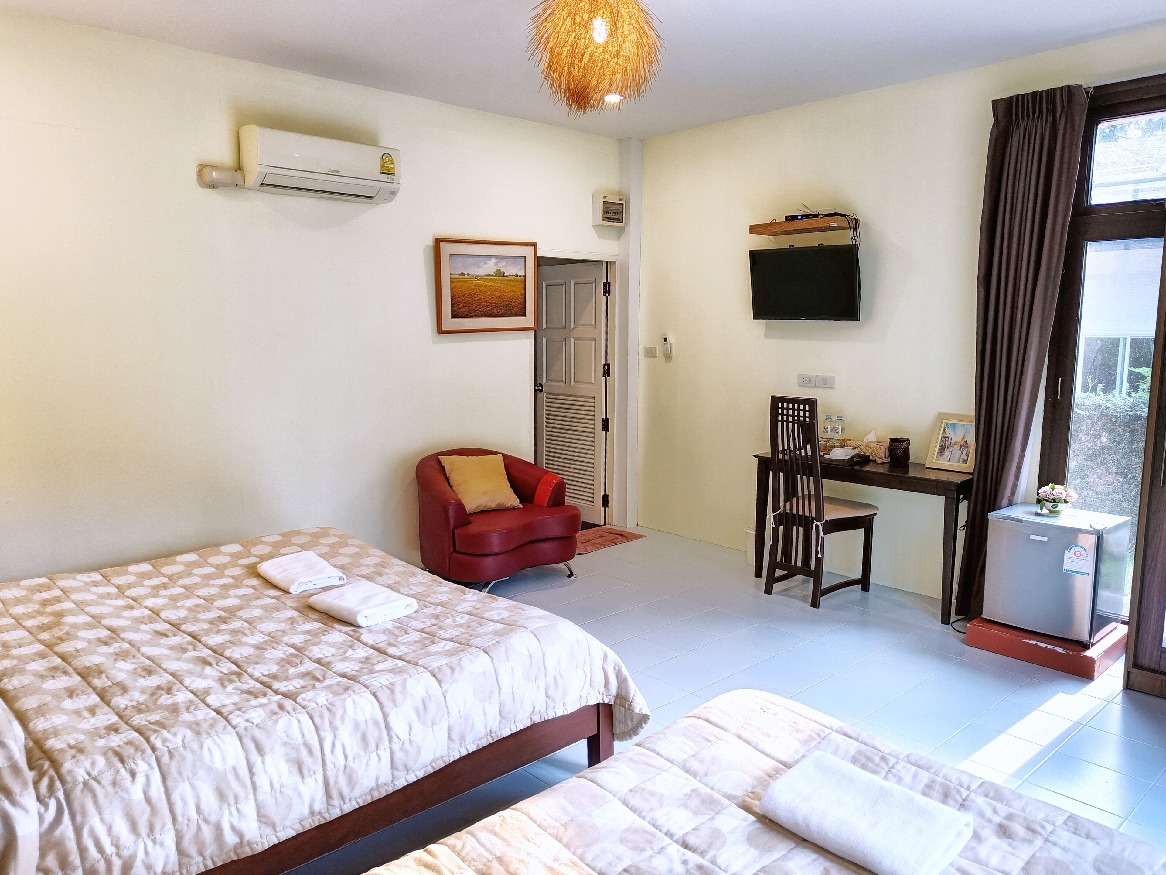 Una habitación de hotel con dos camas, un escritorio, una silla, un televisor y un refrigerador.