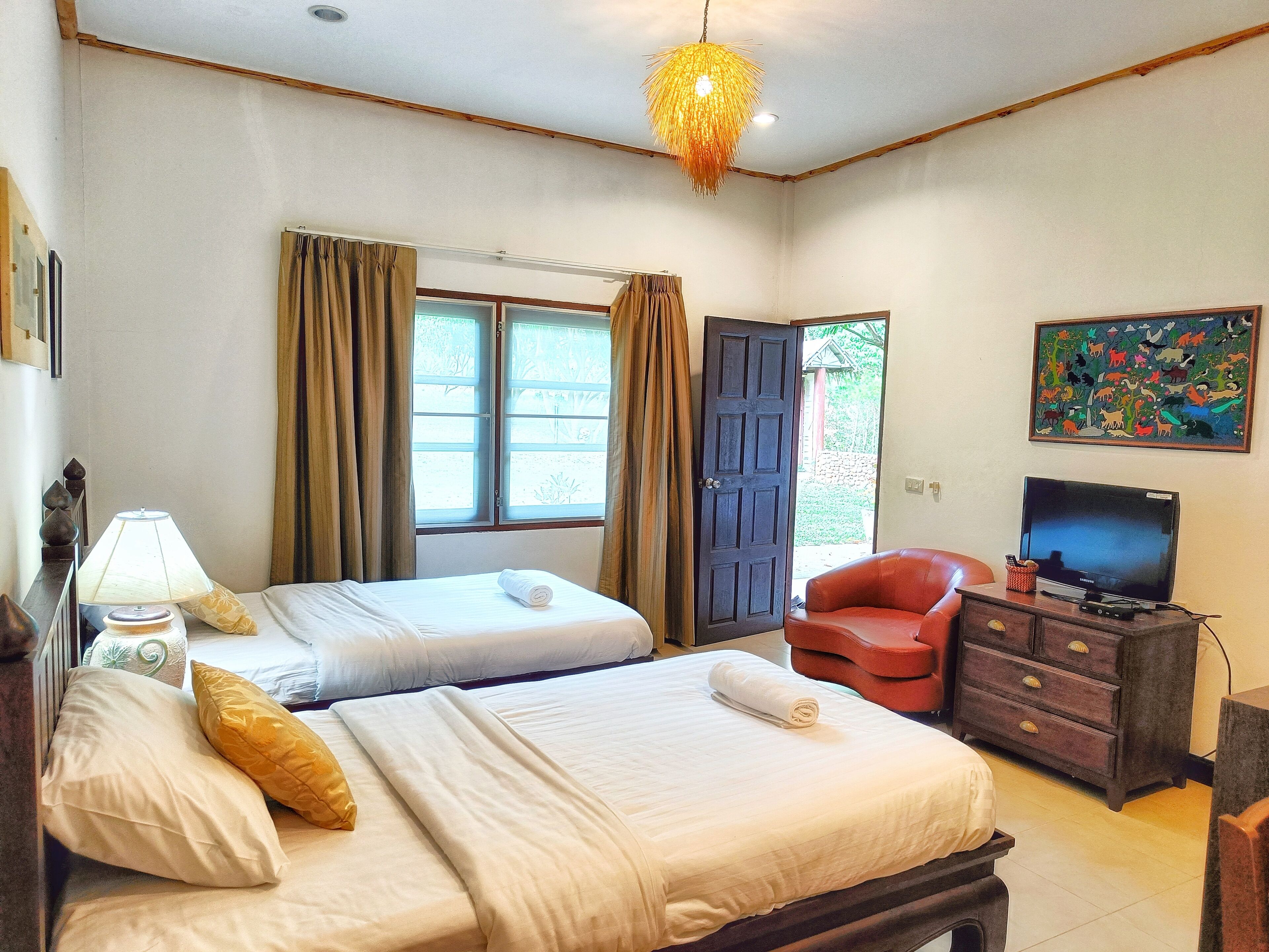 A hotel room with two beds, a television, a desk, and a painting on the wall.