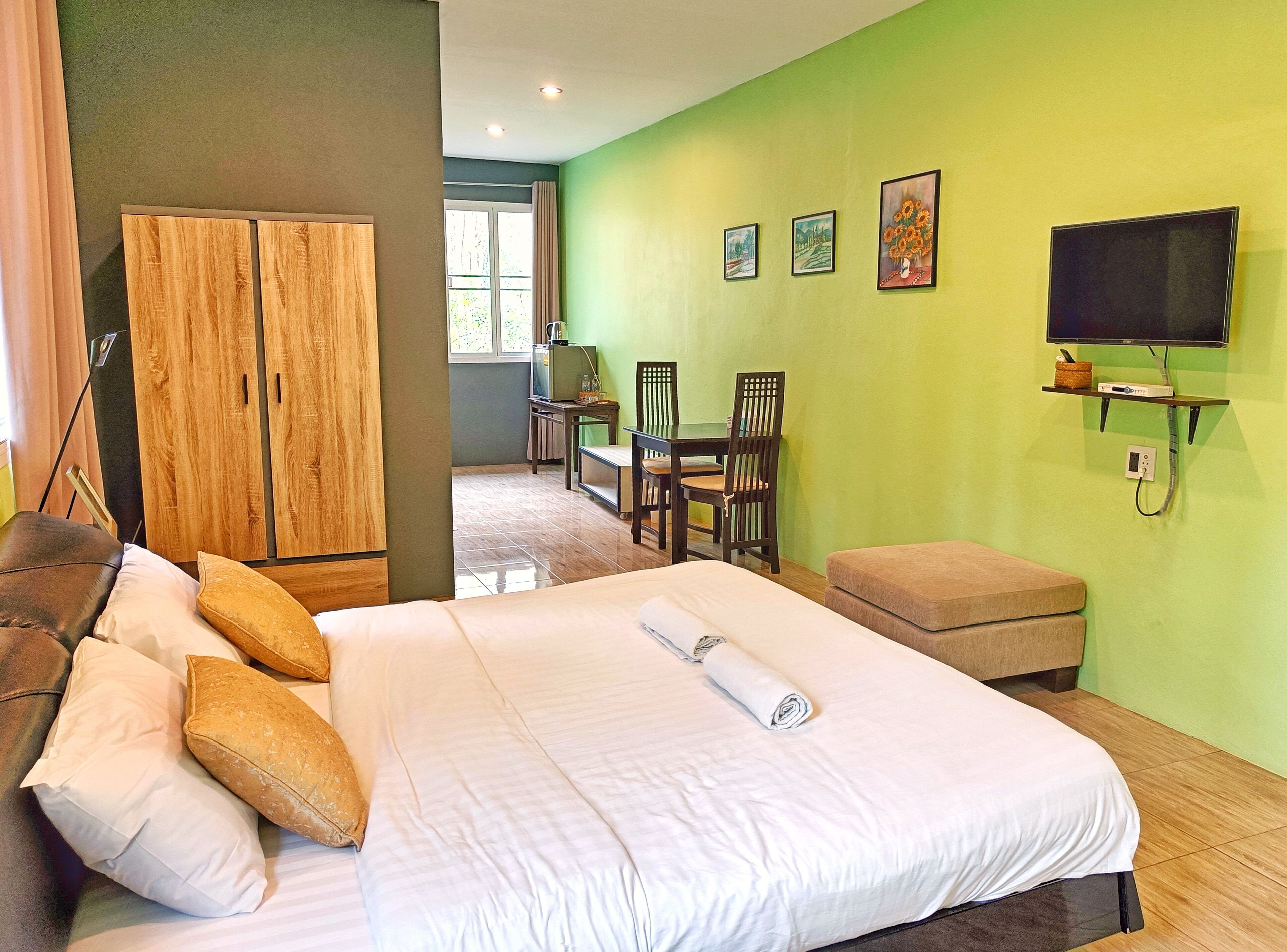 Una habitación de hotel con cama, escritorio, silla, televisor y armario.