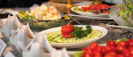 Un buffet proposant une variété de plats, notamment des salades, des fruits et des légumes.