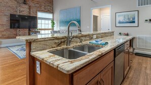 Una cocina con encimera de granito, pileta de acero inoxidable y armarios de madera.