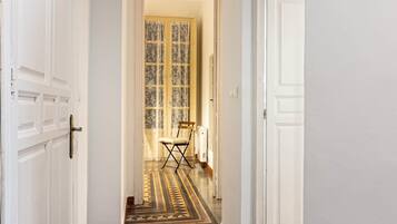 Un couloir avec des portes blanches, un sol à motifs et une chaise au loin.